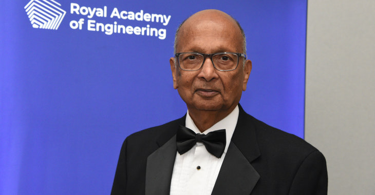 Dr Paulraj stood in front of a blue banner with the Royal Academy of Engineering logo