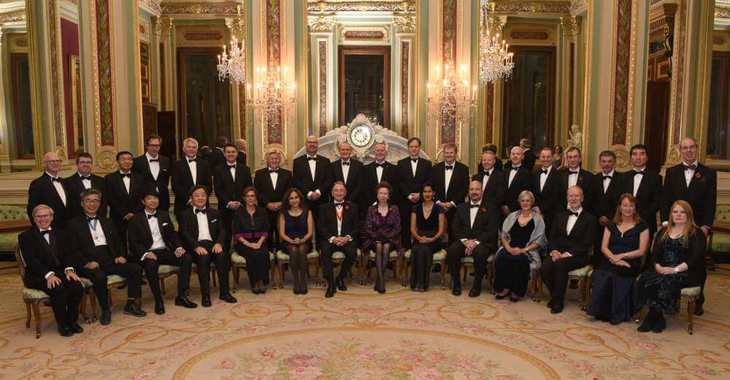 Formal group shot of 33 people, in black tie, facing camera in two rows