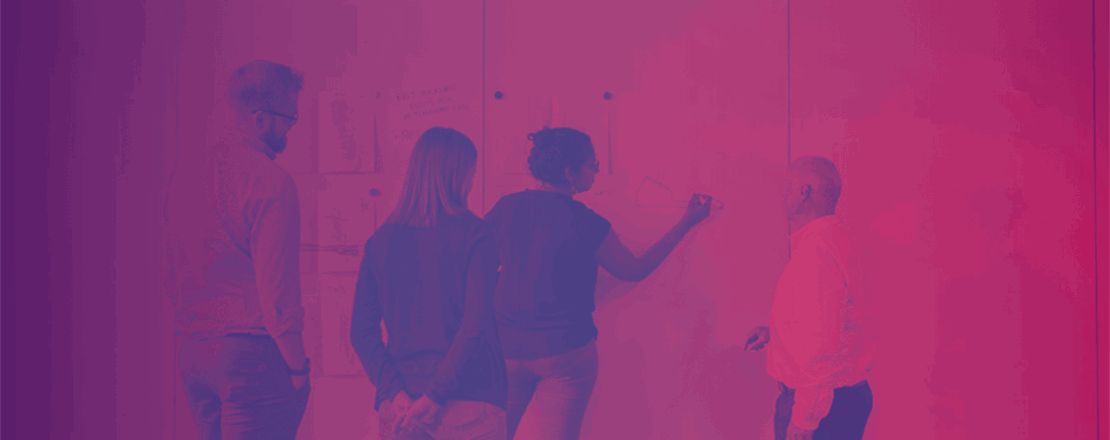 Pink and indigo duotone of a woman writing on a whiteboard. Three other people are gathered around her looking at her work. 